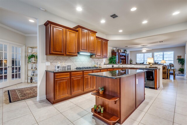 kitchen with kitchen peninsula, french doors, stainless steel gas cooktop, sink, and a kitchen island