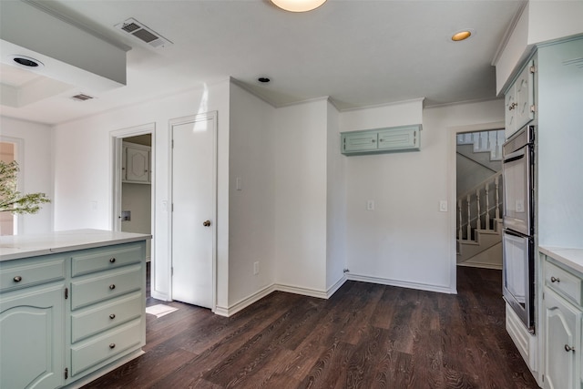 kitchen featuring dark hardwood / wood-style flooring, crown molding, and double oven