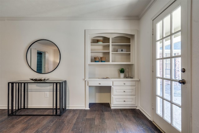 unfurnished office featuring dark wood-type flooring, built in desk, and ornamental molding