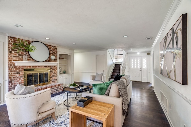 living room featuring a textured ceiling, dark hardwood / wood-style floors, a brick fireplace, and ornamental molding