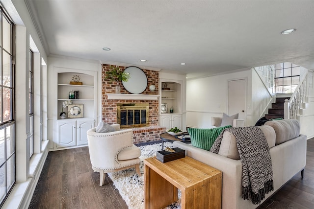 living room featuring a fireplace, built in shelves, dark hardwood / wood-style flooring, and ornamental molding