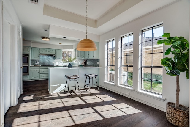 kitchen with plenty of natural light, a raised ceiling, kitchen peninsula, and tasteful backsplash