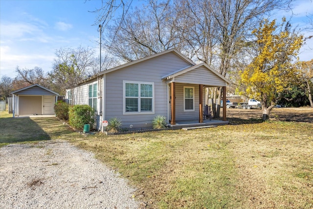 view of front of property featuring covered porch, an outbuilding, a garage, and a front lawn