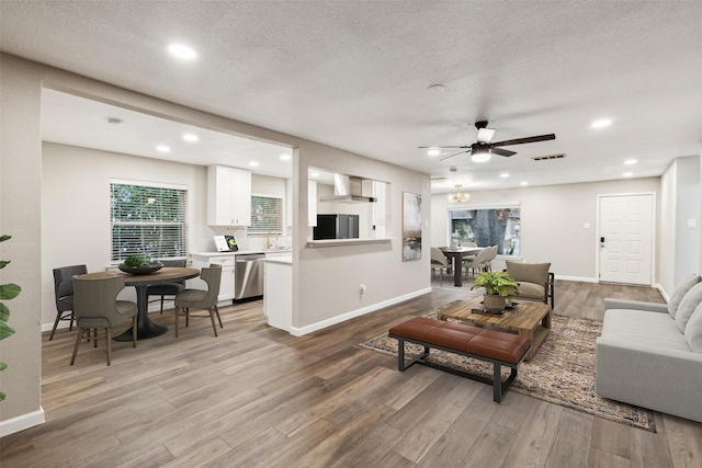 living room featuring ceiling fan, light hardwood / wood-style floors, and a textured ceiling