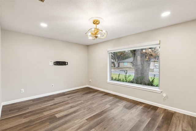 spare room with dark wood-type flooring and a notable chandelier