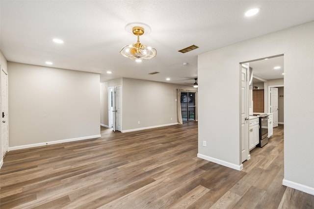 unfurnished living room with dark hardwood / wood-style floors and ceiling fan with notable chandelier