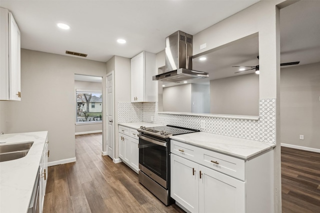 kitchen with white cabinets, light stone counters, wall chimney exhaust hood, and stainless steel electric range