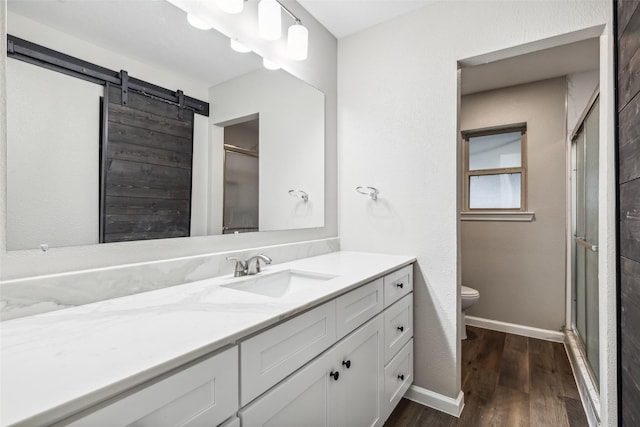 bathroom with vanity, wood-type flooring, a shower with shower door, and toilet