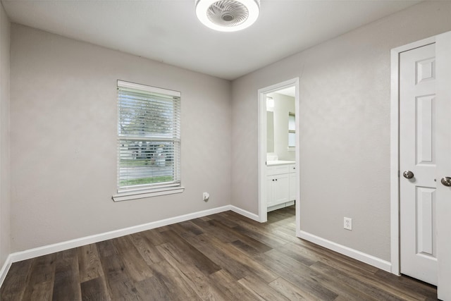 unfurnished bedroom featuring ensuite bathroom and dark hardwood / wood-style floors