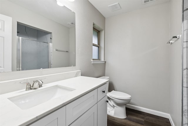 bathroom with a shower with door, vanity, wood-type flooring, and toilet