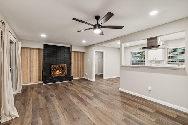 unfurnished living room with ceiling fan, a fireplace, and dark hardwood / wood-style floors