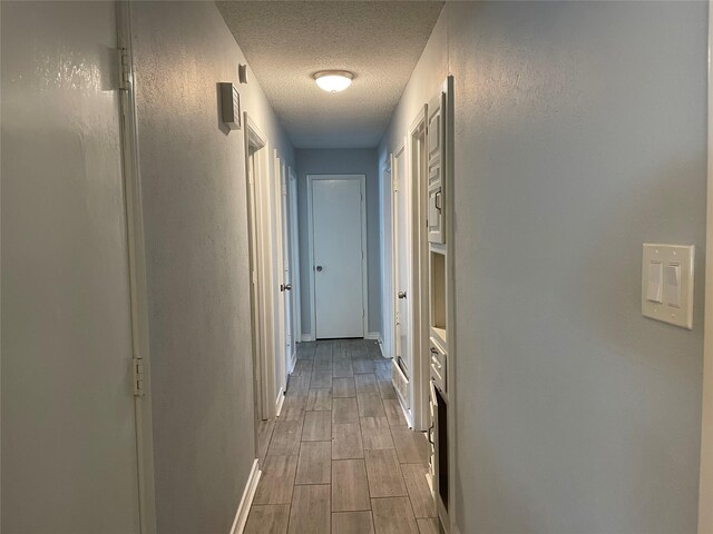 hall with light hardwood / wood-style flooring and a textured ceiling