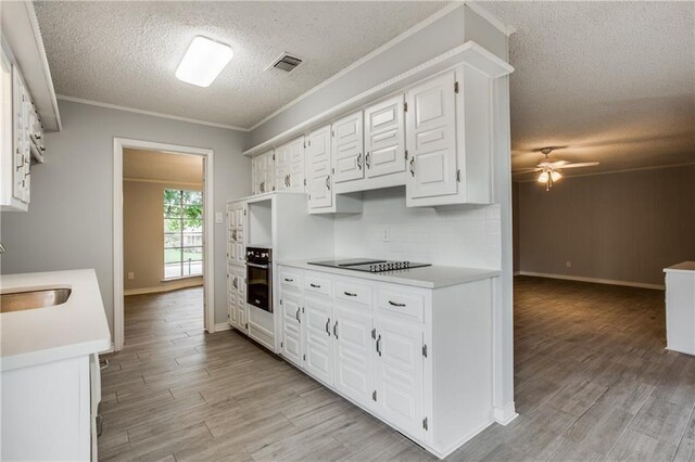 kitchen with black appliances, sink, light wood-type flooring, a textured ceiling, and white cabinetry