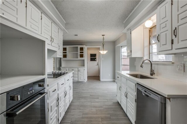 kitchen with black appliances, white cabinets, sink, and hanging light fixtures