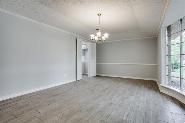 spare room with a textured ceiling, a notable chandelier, and light wood-type flooring