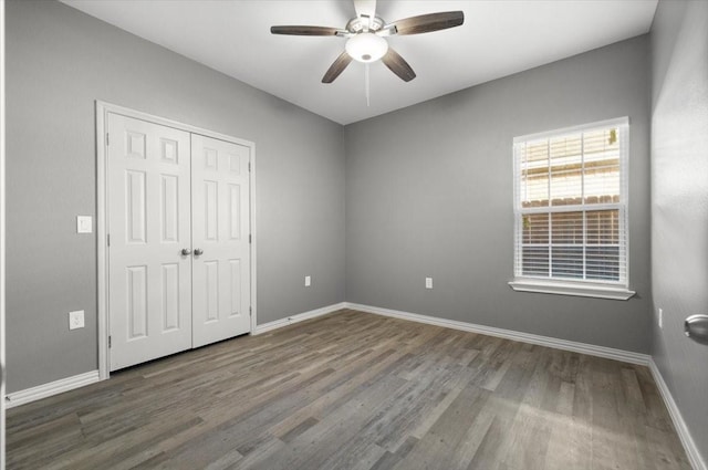 unfurnished bedroom with ceiling fan, a closet, and wood-type flooring