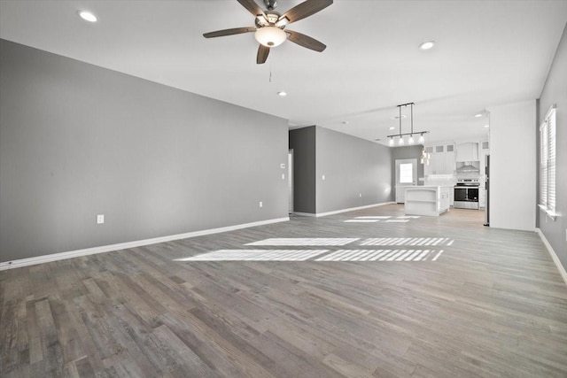 unfurnished living room featuring ceiling fan and light wood-type flooring