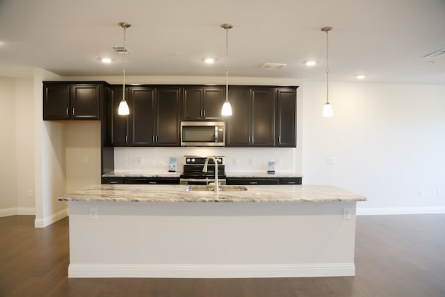 kitchen featuring dark hardwood / wood-style flooring, a center island with sink, pendant lighting, and appliances with stainless steel finishes