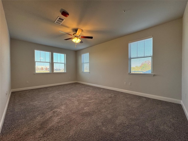 spare room with dark colored carpet, ceiling fan, and plenty of natural light