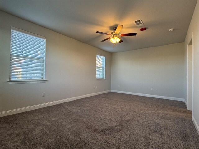 spare room with dark colored carpet and ceiling fan