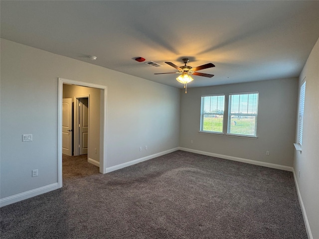 unfurnished room with dark colored carpet and ceiling fan