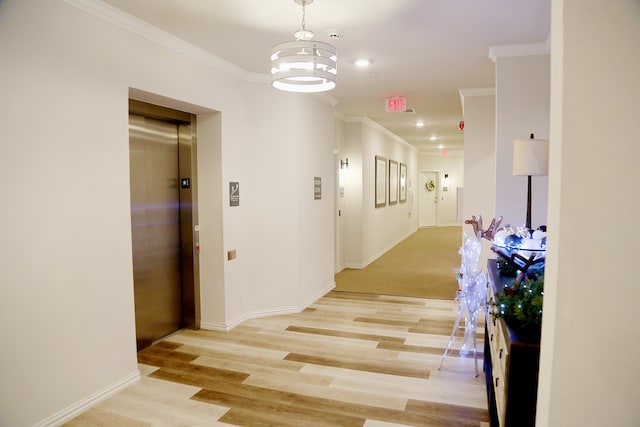 corridor featuring elevator, ornamental molding, light wood-type flooring, and an inviting chandelier