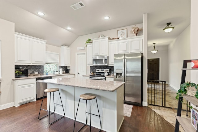 kitchen with white cabinets, appliances with stainless steel finishes, dark hardwood / wood-style floors, and a kitchen island