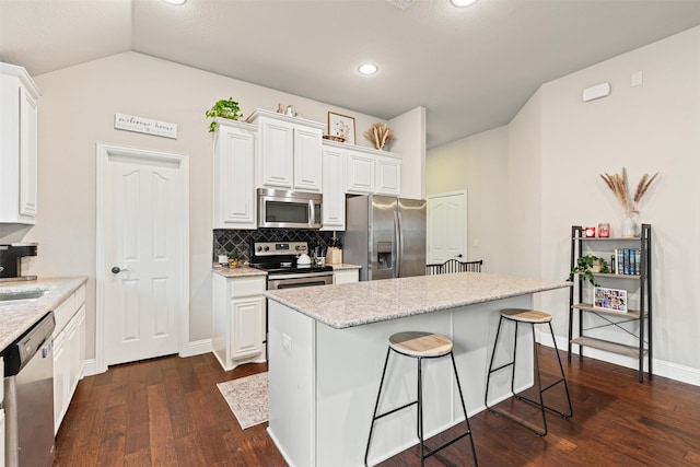 kitchen with a center island, dark hardwood / wood-style flooring, white cabinets, and appliances with stainless steel finishes