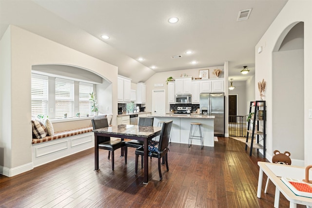 dining area with ceiling fan, lofted ceiling, and dark wood-type flooring