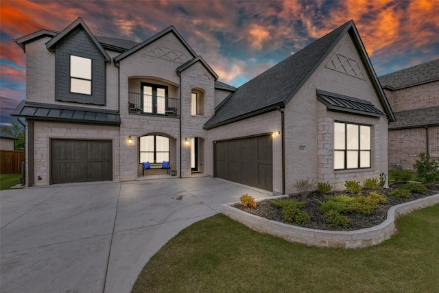 view of front of house featuring metal roof, a balcony, concrete driveway, stone siding, and a standing seam roof