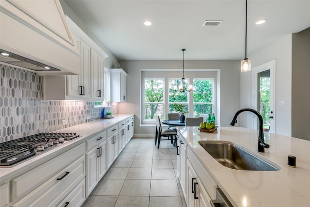 kitchen featuring white cabinetry, stainless steel gas stovetop, custom exhaust hood, and a sink