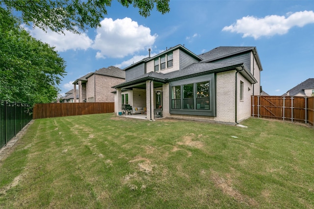 rear view of house with a patio area, a fenced backyard, brick siding, and a yard