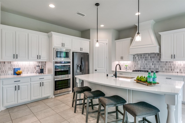 kitchen with stainless steel appliances, custom range hood, white cabinetry, and light countertops