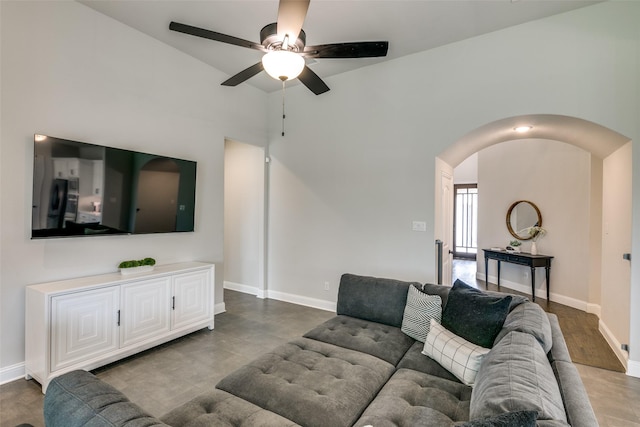 living area featuring baseboards, arched walkways, and ceiling fan