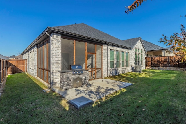 rear view of property featuring an outdoor kitchen, a patio area, and a lawn