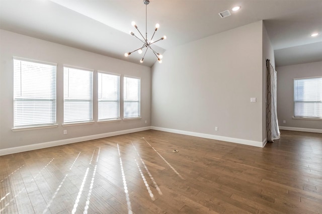 unfurnished room with an inviting chandelier, vaulted ceiling, and dark hardwood / wood-style floors