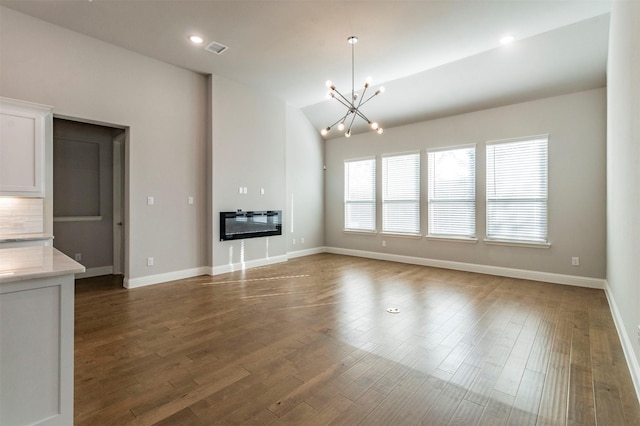 unfurnished living room featuring dark wood-type flooring, a chandelier, and vaulted ceiling