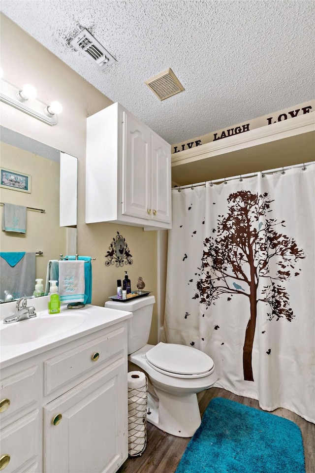 bathroom with hardwood / wood-style flooring, vanity, toilet, and a textured ceiling