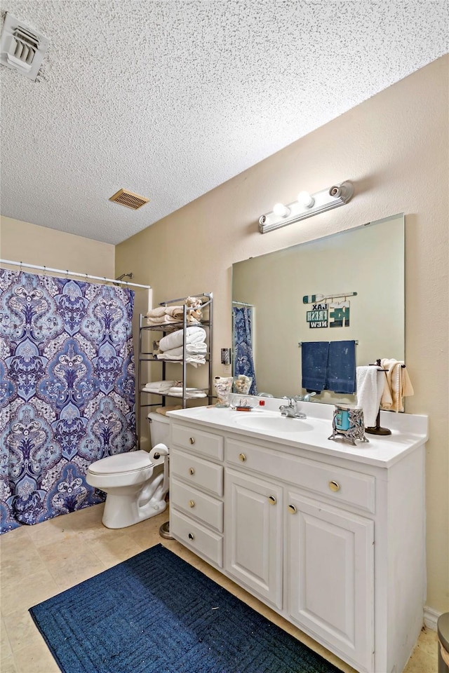 bathroom featuring tile patterned floors, vanity, a textured ceiling, and toilet