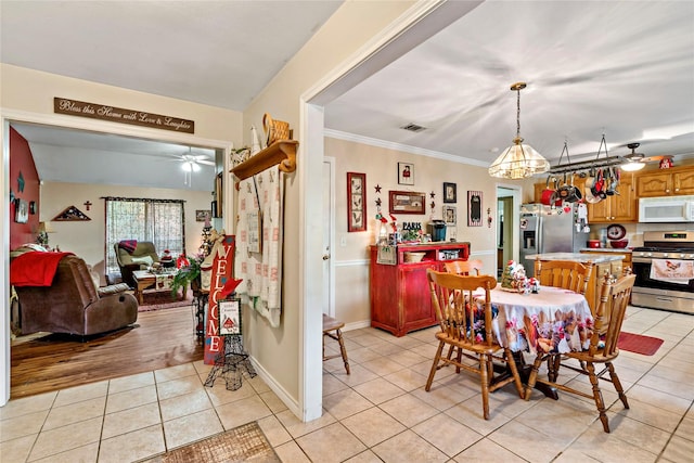 tiled dining space with ceiling fan and ornamental molding