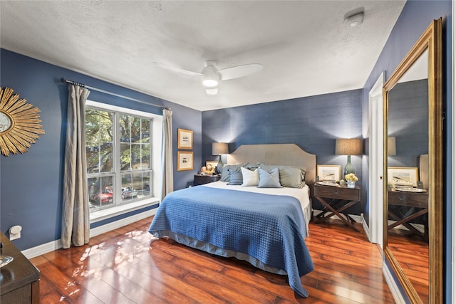 bedroom with ceiling fan, dark hardwood / wood-style flooring, and a textured ceiling