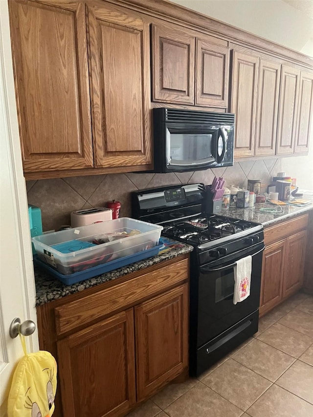 kitchen with decorative backsplash, light tile patterned floors, and black appliances