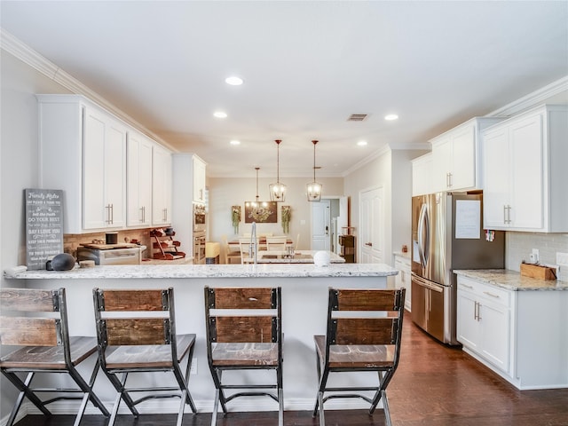 kitchen with white cabinets, light stone counters, hanging light fixtures, and a breakfast bar area