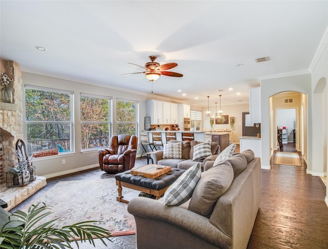 living room featuring a fireplace, dark hardwood / wood-style floors, ceiling fan, and ornamental molding