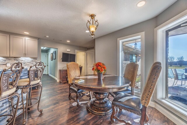 dining space featuring a textured ceiling and dark wood-type flooring