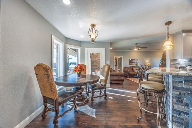 dining area with a textured ceiling, ceiling fan, and dark wood-type flooring