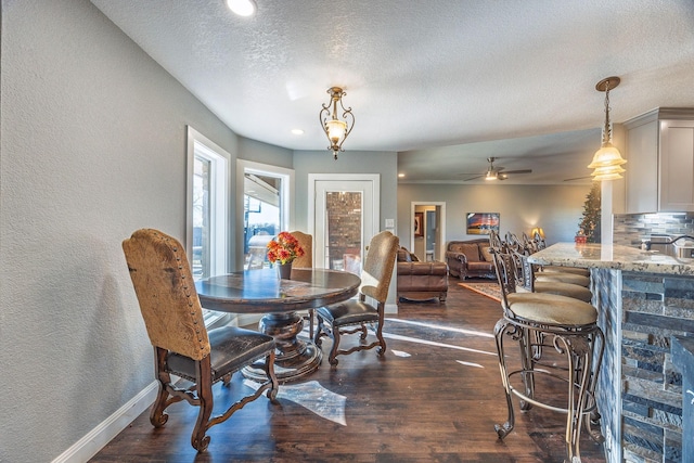 dining space featuring dark wood-type flooring, ceiling fan, and a textured ceiling