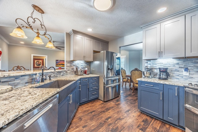 kitchen featuring sink, ornamental molding, appliances with stainless steel finishes, dark hardwood / wood-style flooring, and pendant lighting