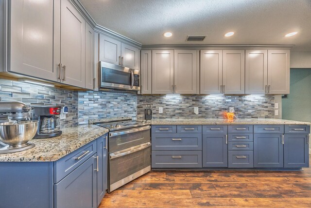 kitchen featuring decorative backsplash, appliances with stainless steel finishes, gray cabinetry, a textured ceiling, and dark hardwood / wood-style floors