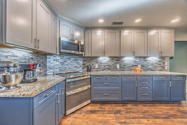 kitchen featuring tasteful backsplash, dark wood-type flooring, gray cabinets, and appliances with stainless steel finishes